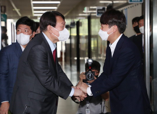 국민의힘 대선 예비후보인 윤석열(왼쪽) 전 검찰총장과 이준석(오른쪽) 당대표가 만나 6일 오전 서울 여의도 국회 당대표실에서 회동한 뒤 악수를 나누고 있다.연합뉴스·국회사진기자단
